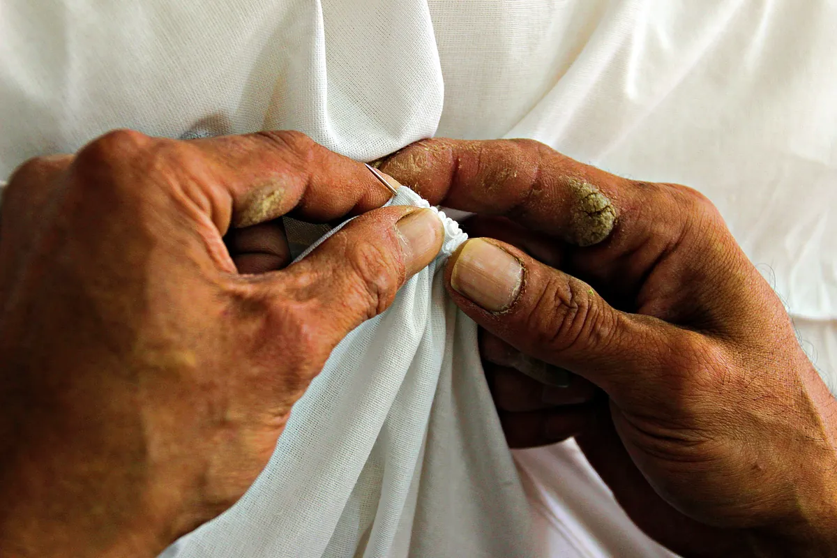 Mani che cuciono a mano un tessuto bianco